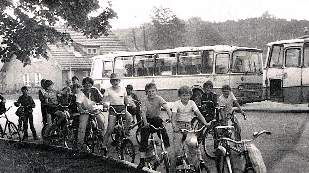 Uczestnicy wycieczki rowerowej na tle dwóch autobusów Autosan H9 z taboru PKS Wałcz parkujących na obecnym targowisku przy ulicy Stanisława Moniuszki w Człopie, lata 1980. Źródło: profil FB THDzwCz